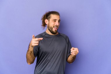 Uzun saçlı genç adam parmaklarıyla öne bakıyor..