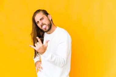 Uzun saçlı genç adam parmaklarıyla taş hareketi gösteriyor.