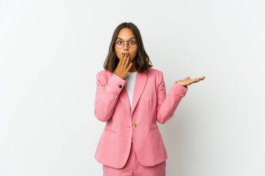 Beyaz arka planda soyutlanmış genç Latin bir kadın işaret parmağıyla işaret ederek gülümsüyor..