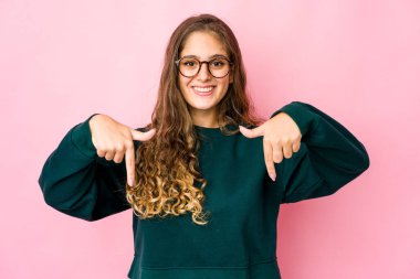 Genç beyaz kadın parmaklarıyla aşağı işaret ediyor, pozitif duygu..