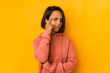 Genç İspanyol kadın sarı şakağı işaret ederek izole edilmiş. Düşünüyor, bir göreve odaklanmış..