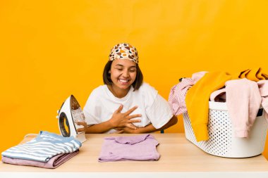 Giysileri ütüleyen genç İspanyol kadın yalnız gülüyor ve eğleniyor..