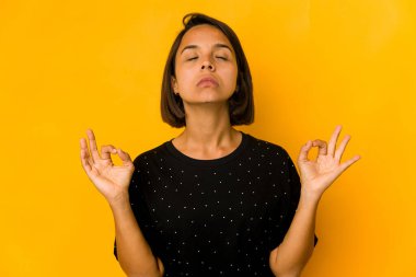 Genç İspanyol kadın, sıkı çalışma gününden sonra sarı gevşemeleri izole ederek yoga yapıyor..