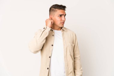 Genç, beyaz, yakışıklı bir adam, izole edilmiş kulakları elleriyle kapatıyor..
