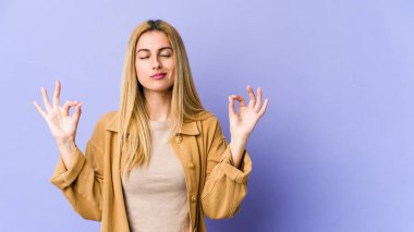 Genç, sarışın, beyaz kadın yoğun bir günün ardından rahatlıyor. Yoga yapıyor..