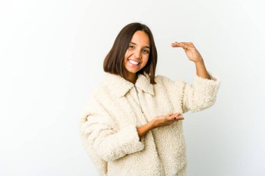 Genç melez kadın işaret parmaklarıyla küçük bir şey tutuyor, gülümsüyor ve kendinden emin..