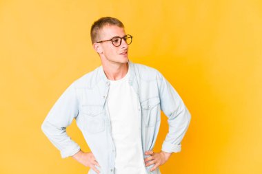 Beyaz tenli yakışıklı, kendine güveni tam. Ellerini kalçasından ayırmıyor..