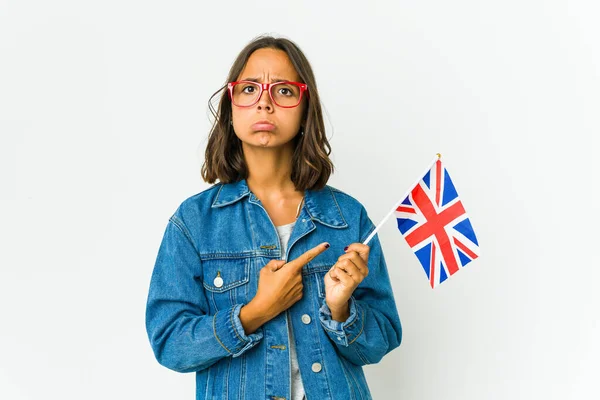 白い背景の点で隔絶された英語の旗を持っている若いラテン語の女性は 2つのオプションの間で選択しようとしています — ストック写真