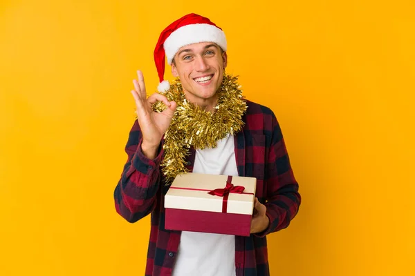 Молодий Білий Чоловік Різдвяним Капелюхом Тримає Подарунок Ізольований Жовтому Тлі — стокове фото