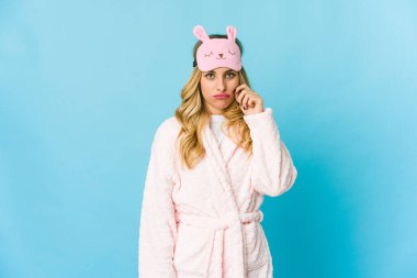 Genç sarışın, beyaz kadın pijama giyiyor. Parmakları dudaklarında, sır saklıyor..