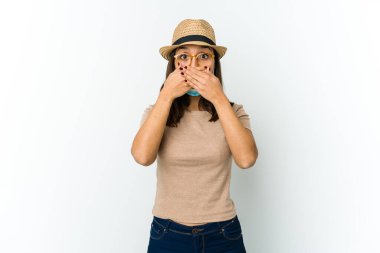 Şapka ve maske takan genç Latin bir kadın beyaz arka planda kapalı kapalı kapalı kapalı kapalı kapalı ağızlı ellerle şok.