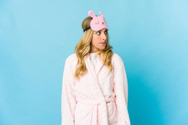 Genç, sarışın, beyaz kadın pijama giyiyor. Kafası karışmış ve kendinden emin değil..