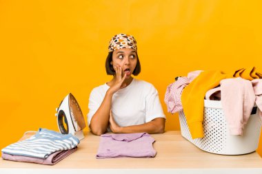 Elbiseleri ütüleyen genç İspanyol kadın gizli bir sıcak fren haberi veriyor ve yan bakıyor.