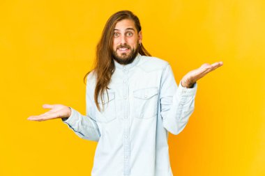 Uzun saçlı genç adam kafası karışmış görünüyor ve bir kopya alanı tutmak için omuz silkiyor..