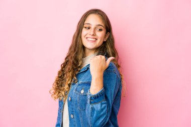 Genç beyaz kadın başparmağıyla işaret ediyor, gülüyor ve kaygısız..