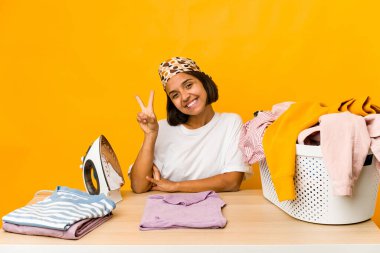 Giysileri ütüleyen genç İspanyol kadın iki numarayı parmaklarıyla gösteriyor..