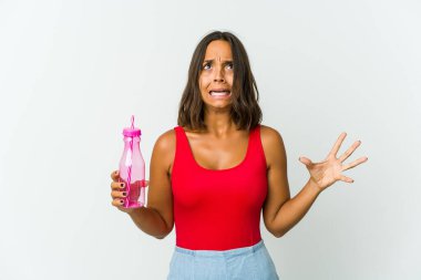 Beyaz arka planda izole edilmiş milkshake 'i tutan genç Latin kadın gökyüzüne haykırıyor, yukarı bakıyor, hayal kırıklığına uğruyor..