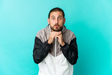 Uzun saçlı genç adam şans için dua ediyor, şaşırmış ve ağzını açıyor..