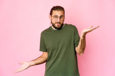 Uzun saçlı genç adam kafası karışmış görünüyor ve bir kopya alanı tutmak için omuz silkiyor..