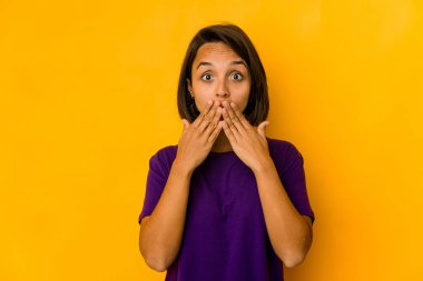 Sarı üzerine izole edilmiş genç İspanyol kadın elleriyle ağzını kapatıyor..