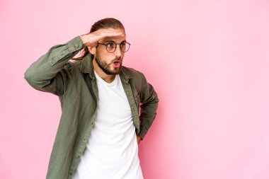 Uzun saçlı genç adam, elini alnında tutarak uzaklara bakıyor..