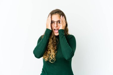 Beyaz bir kadın yüzünün yarısını avuç içiyle kaplayarak eğleniyor..