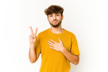 Beyaz arka planda genç bir Arap yemin ediyor, elini göğsüne koyuyor..