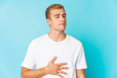 Beyaz tenli yakışıklı adam karnına dokunuyor, nazikçe gülümsüyor, yemek yiyor ve tatmin oluyor..