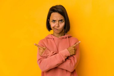 Sarı noktalarda izole edilmiş genç İspanyol kadın iki seçenek arasında seçim yapmaya çalışıyor..