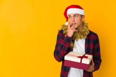 Sarı arka planda izole edilmiş bir hediye tutan Kafkasyalı genç adam bir şeyin fotokopi odasına baktığını düşünerek rahatladı..