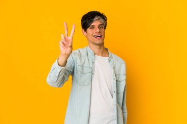 Genç, sıska İspanyol adam parmaklarıyla iki numarayı gösteriyor..