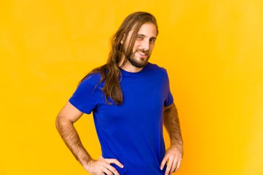 Uzun saçlı genç adam gülümseyen, neşeli ve hoş bakışlarını yana çevir..