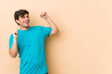 Havalı genç adam özel bir günü kutluyor, atlıyor ve enerjiyle kollarını kaldırıyor..