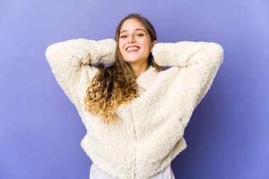 Beyaz tenli tatlı bir kadın. Kendine güveniyor. Elleri başının arkasında..