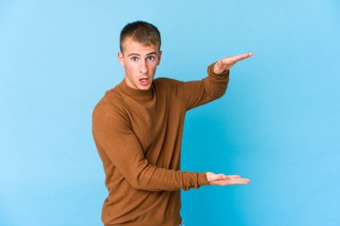 Genç, beyaz, yakışıklı bir adam ellerinin arasında bir kopya alanı tutarken şok olmuş ve hayrete düşmüştü..