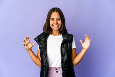 Genç melez kadın elinde avuç içi bir şeyle kameraya sunuyor..