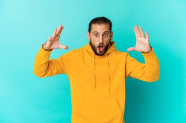 Uzun saçlı genç adam zaferi ya da başarıyı kutluyor gibi görünüyor. Şaşırdı ve şok oldu..