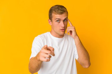 Genç, beyaz, yakışıklı bir adam şakağı parmağıyla işaret ediyor. Düşünüyor, bir göreve odaklanıyor..