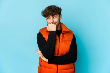 Mavi arka planda genç bir Arap tırnaklarını yiyor, gergin ve endişeli..