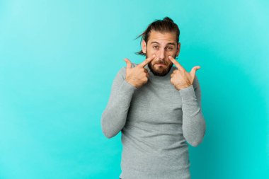 Uzun saçlı genç adam ağlıyor, bir şeyden memnun değil, acı ve kafa karışıklığı konsepti..