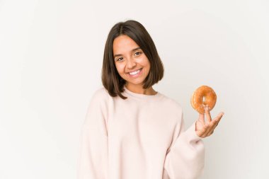 Genç İspanyol kadın donut yerken mutlu, güler yüzlü ve neşeli.