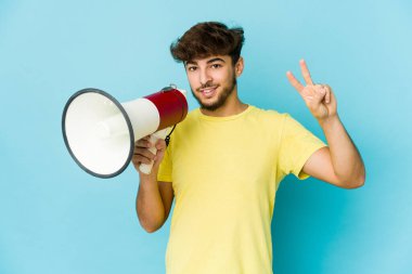 İki numarayı parmaklarıyla gösteren bir megafon tutan genç bir Arap..