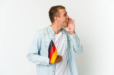Beyaz arka planda izole edilmiş Alman bayrağı tutan genç beyaz bir adam bağırıyor ve avuç içini açık tutuyor..