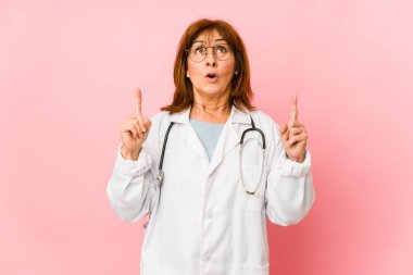 Orta yaşlı, beyaz, doktor bir kadın izole edilmiş, ağzı açık bir şekilde işaret ediyor..
