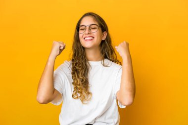 Genç beyaz kadın zafer, tutku ve coşkuyu kutluyor, mutlu bir ifade..