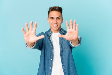 Beyaz tenli yakışıklı yalnız başına on numarayı elleriyle gösteriyor..