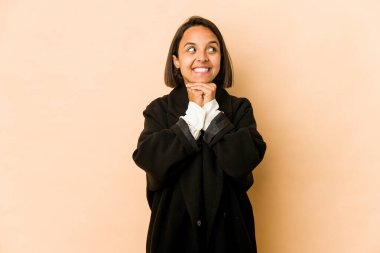 İzole edilmiş genç İspanyol kadın ellerini çenesinin altında tutuyor ve mutlu bir şekilde yan tarafa bakıyor..