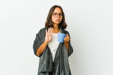 Beyaz arka planda battaniyeli genç Latin kadın elini uzatmış, dur işareti göstererek seni engelliyor..