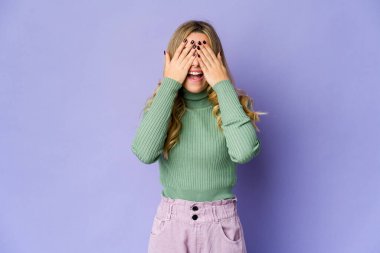 Beyaz tenli sarışın kadın elleriyle gözlerini kapatıyor. Gülümsüyor ve bir sürpriz bekliyor..