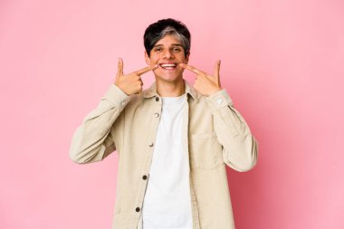 Genç, sıska İspanyol adam gülümsüyor, parmaklarını ağzına doğrultuyor..